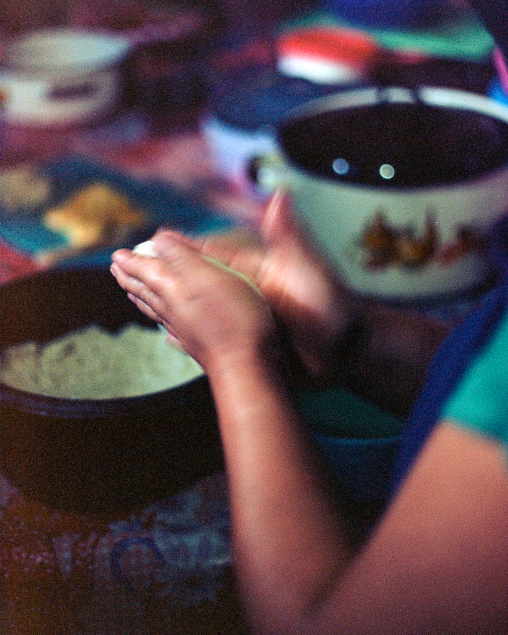Close-up of hands and bowls with food in dim lighting