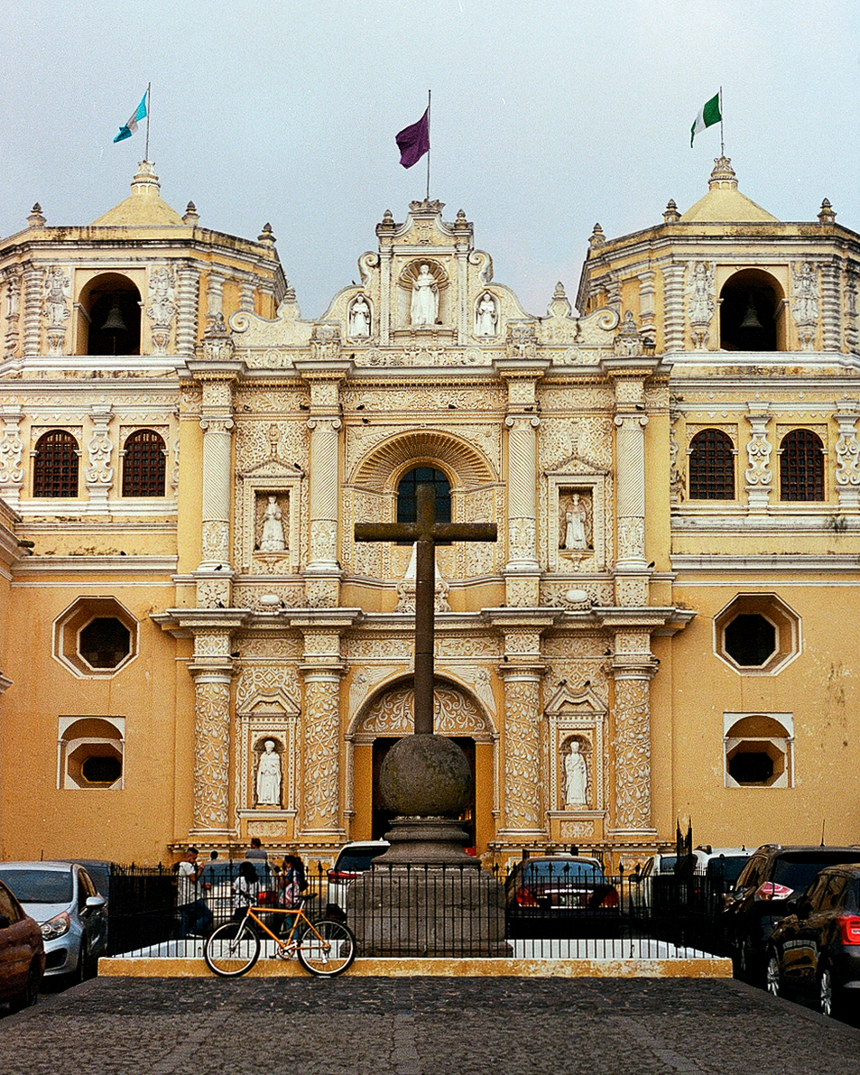 Yellow colonial church with ornate architecture and wooden cross