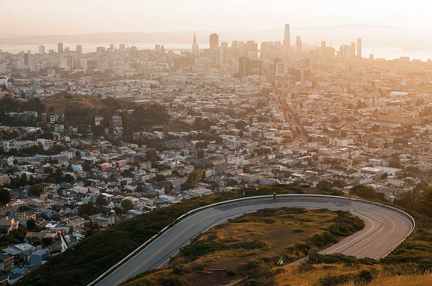 Aerial view of San Francisco skyline at golden hour with curved road in foreground