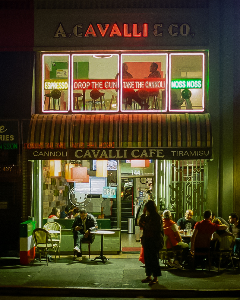Cavalli Cafe at night with neon signs and people sitting outside